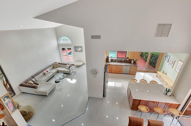 tiled living room with sink and a high ceiling