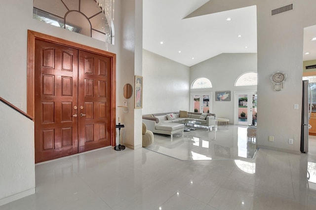 foyer featuring light tile patterned floors and high vaulted ceiling