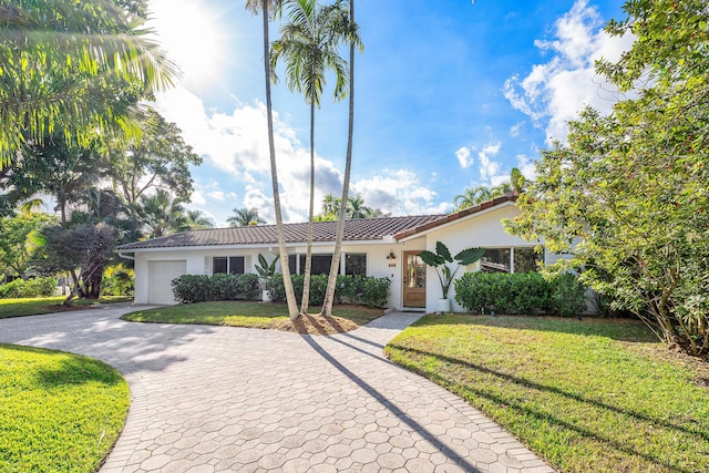 view of front facade with a garage, a front yard, decorative driveway, and a tiled roof