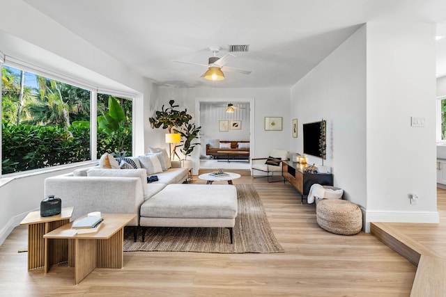 living room with ceiling fan, baseboards, visible vents, and light wood-style floors