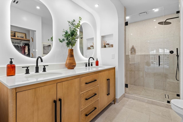 bathroom with a stall shower, visible vents, a sink, and double vanity