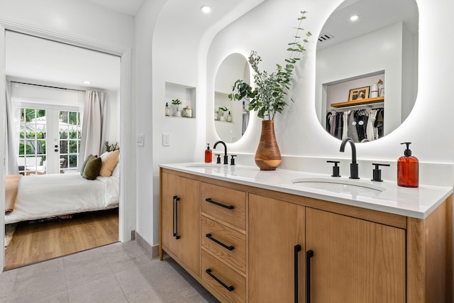 bathroom featuring connected bathroom, french doors, visible vents, and a sink