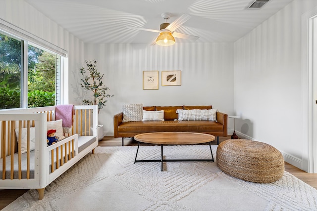 living area with visible vents, ceiling fan, baseboards, and wood finished floors