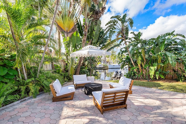 view of patio featuring an outdoor hangout area, a water view, and fence