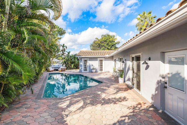 view of swimming pool with a fenced in pool, an outbuilding, and a patio