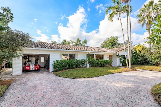 ranch-style house featuring brick siding, a front lawn, an attached garage, and a tile roof