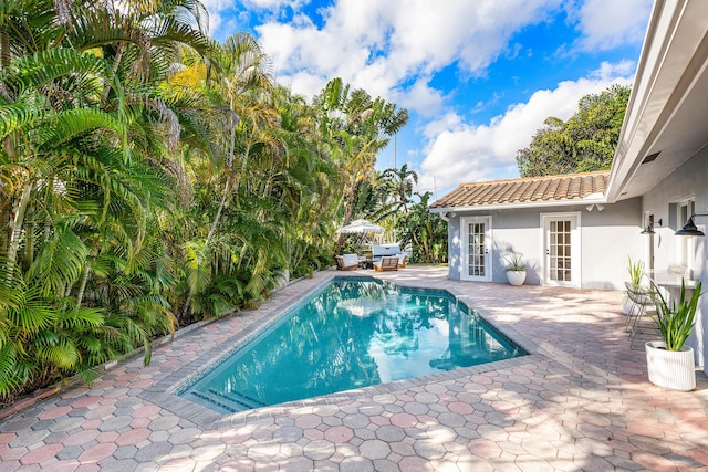 outdoor pool featuring an outbuilding, a patio, area for grilling, and a storage structure