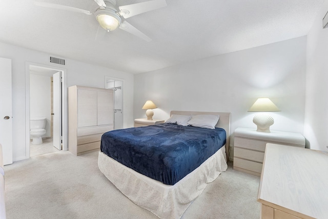 bedroom with ensuite bath, ceiling fan, and light colored carpet