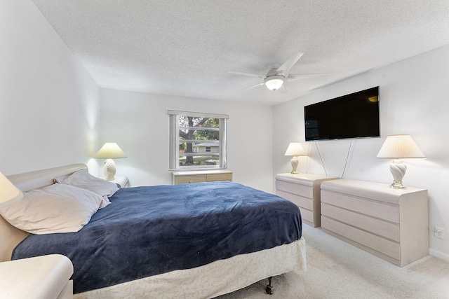 bedroom featuring ceiling fan, light colored carpet, and a textured ceiling