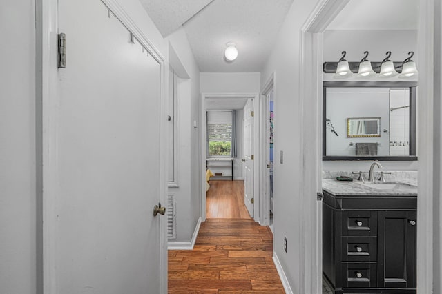 corridor featuring dark hardwood / wood-style flooring, sink, and a textured ceiling