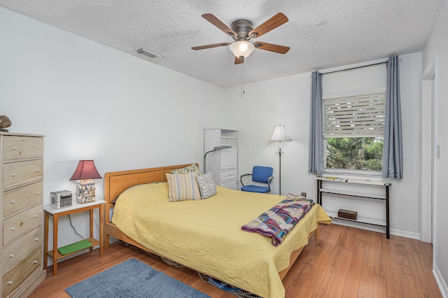 bedroom featuring hardwood / wood-style floors, ceiling fan, and a textured ceiling