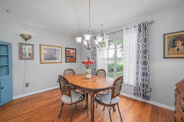 dining room with wood-type flooring, a textured ceiling, and an inviting chandelier