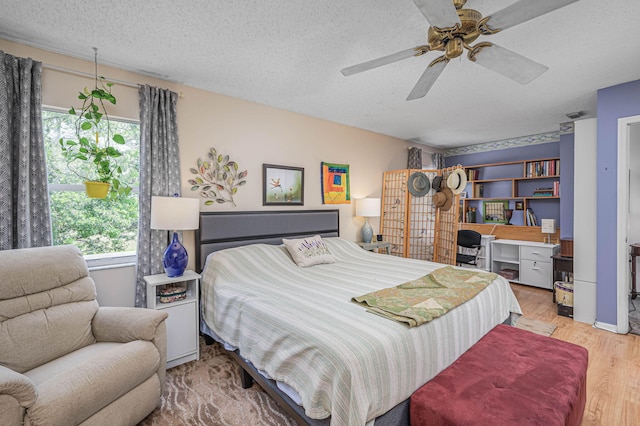 bedroom featuring a textured ceiling, light wood-type flooring, multiple windows, and ceiling fan