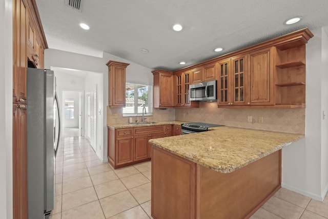 kitchen with kitchen peninsula, stainless steel appliances, sink, light tile patterned floors, and lofted ceiling