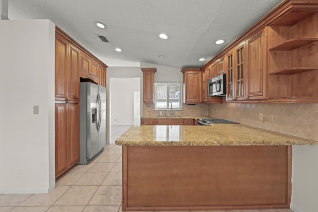 kitchen featuring sink, kitchen peninsula, vaulted ceiling, light tile patterned flooring, and appliances with stainless steel finishes