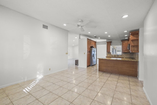 kitchen featuring stainless steel fridge with ice dispenser, light tile patterned floors, ceiling fan, and light stone counters