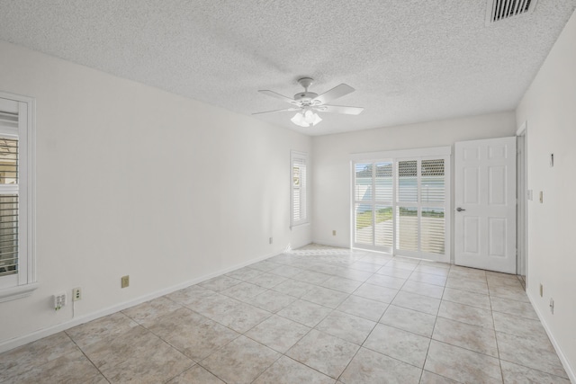 spare room with ceiling fan, light tile patterned floors, and a textured ceiling