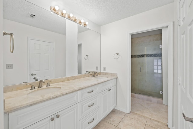 bathroom featuring tile patterned floors, vanity, a shower with shower door, and a textured ceiling