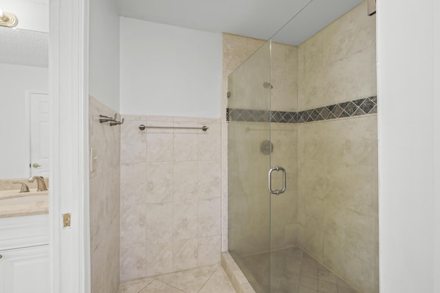 bathroom featuring tile patterned floors, vanity, a shower with shower door, and a textured ceiling