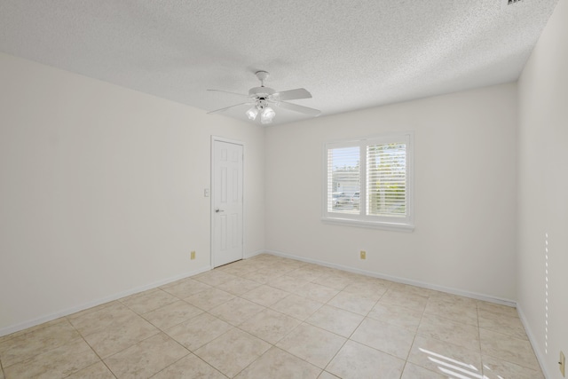 spare room with ceiling fan, light tile patterned floors, and a textured ceiling