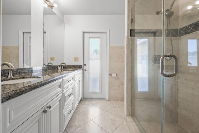 bathroom with tile patterned floors, vanity, a shower with shower door, and tile walls