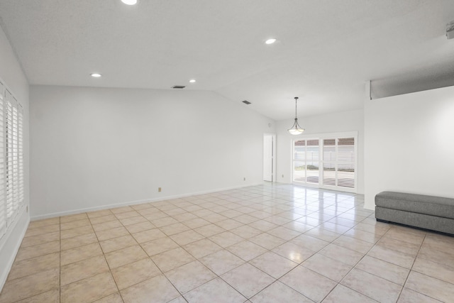 empty room featuring lofted ceiling and light tile patterned flooring