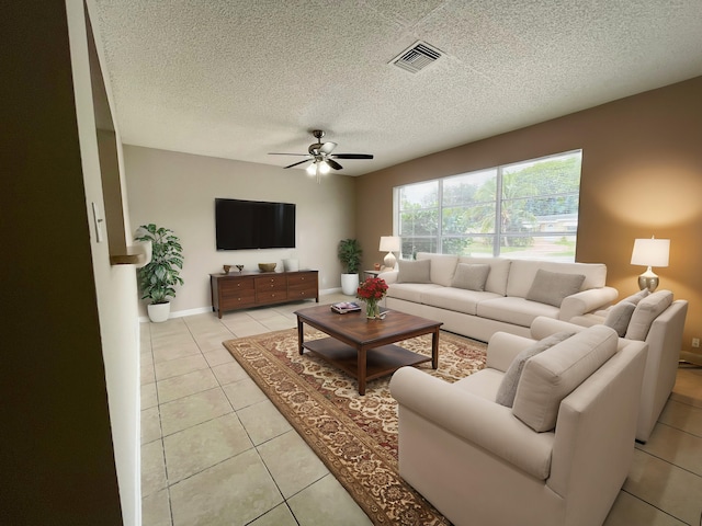 living room featuring ceiling fan, light tile patterned flooring, and a textured ceiling