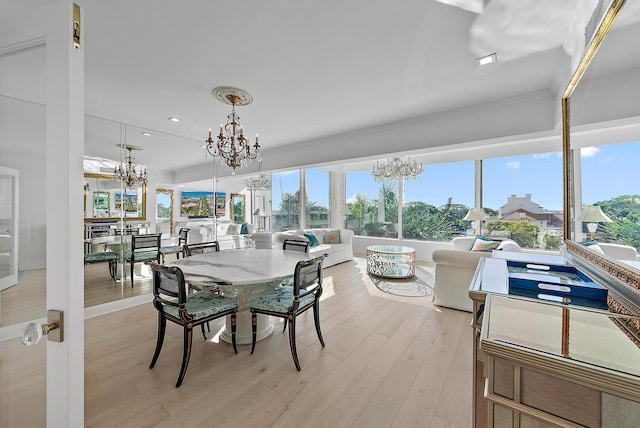 dining space featuring light wood-type flooring, ornamental molding, and a chandelier