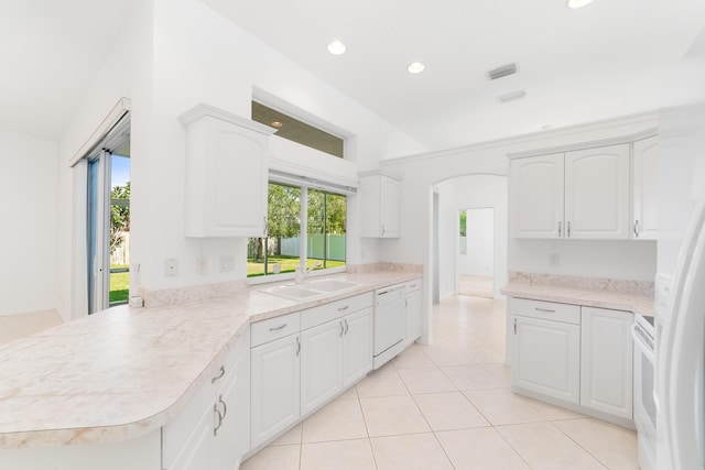 kitchen with sink, light tile patterned flooring, kitchen peninsula, white appliances, and white cabinets