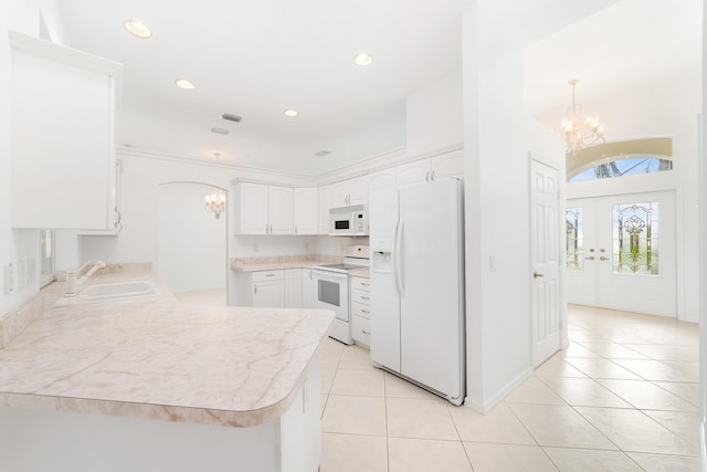 kitchen with white appliances, sink, light tile patterned floors, white cabinets, and hanging light fixtures