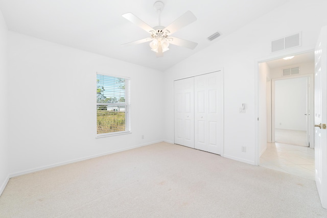 unfurnished bedroom featuring ceiling fan, lofted ceiling, light carpet, and a closet