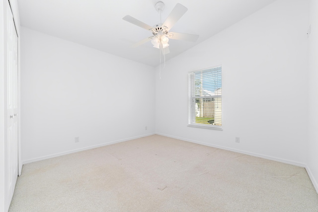 empty room featuring ceiling fan, light colored carpet, and vaulted ceiling