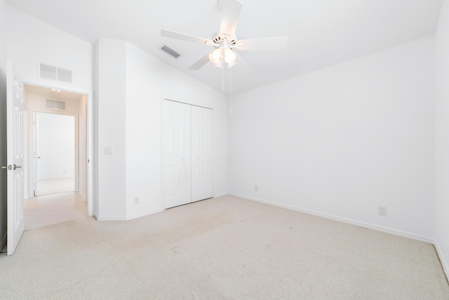 unfurnished bedroom with ceiling fan, a closet, light colored carpet, and lofted ceiling