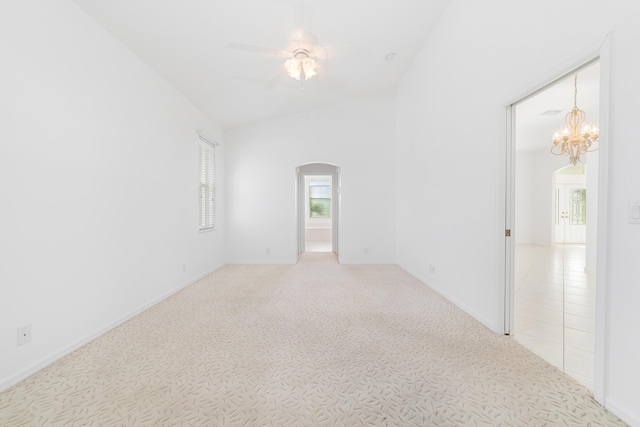 carpeted empty room with ceiling fan with notable chandelier and vaulted ceiling