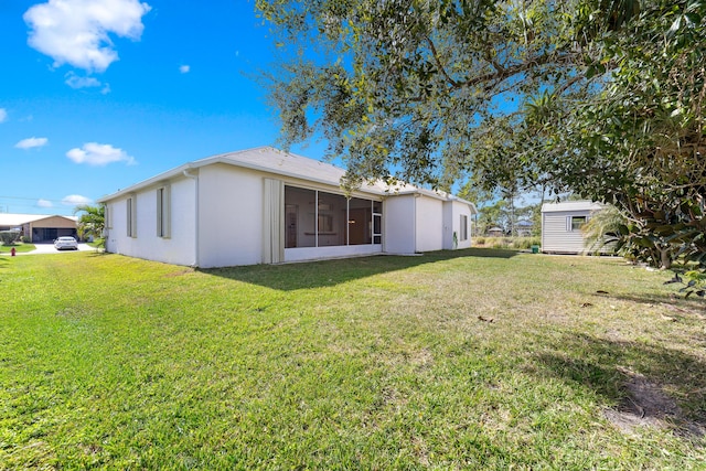 rear view of property featuring a lawn and a storage shed