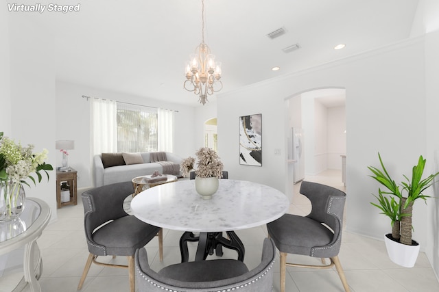 dining area with light tile patterned floors, ornamental molding, and an inviting chandelier