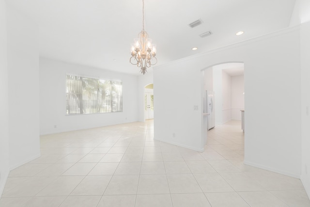 empty room featuring ornamental molding, a notable chandelier, and light tile patterned flooring