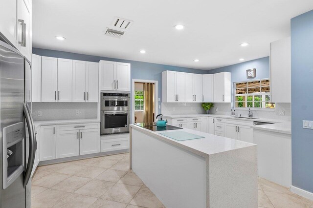 kitchen with a wealth of natural light, white cabinetry, sink, and appliances with stainless steel finishes