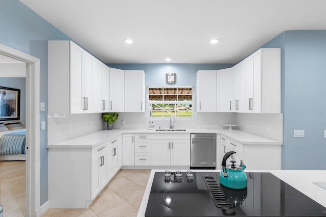 kitchen with cooktop, sink, light tile patterned floors, dishwasher, and white cabinetry