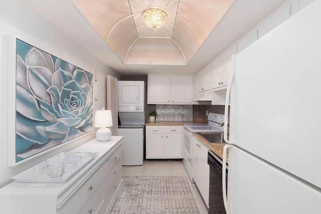 kitchen with a raised ceiling, backsplash, stacked washer / dryer, white appliances, and white cabinets