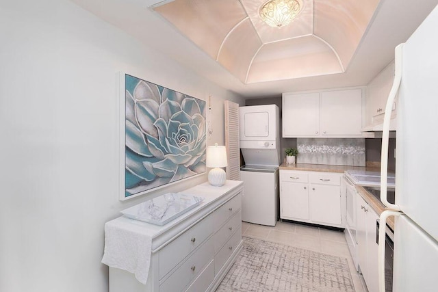 kitchen with white cabinets, light tile patterned flooring, backsplash, and stacked washer and clothes dryer