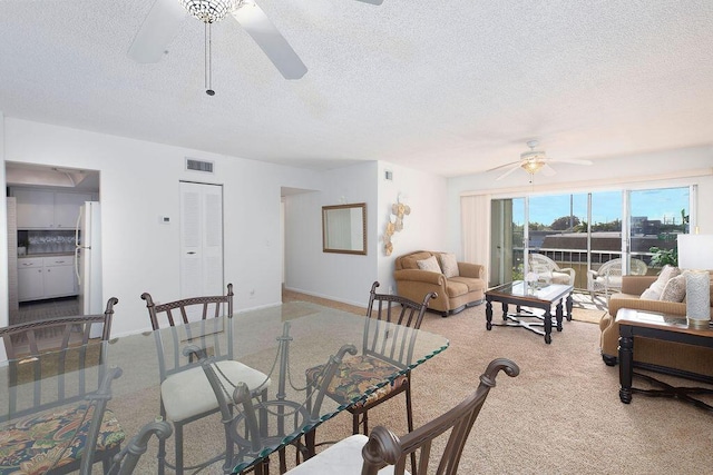 dining area featuring ceiling fan, light colored carpet, and a textured ceiling