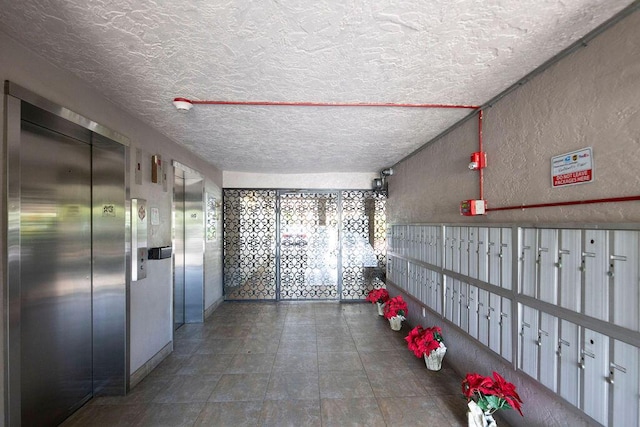 hallway featuring a textured ceiling and elevator