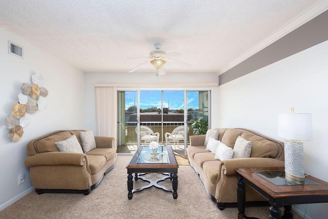 living room featuring a textured ceiling, light colored carpet, ceiling fan, and ornamental molding