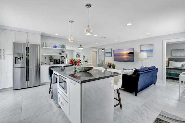 kitchen featuring a center island, white cabinetry, a breakfast bar area, and appliances with stainless steel finishes