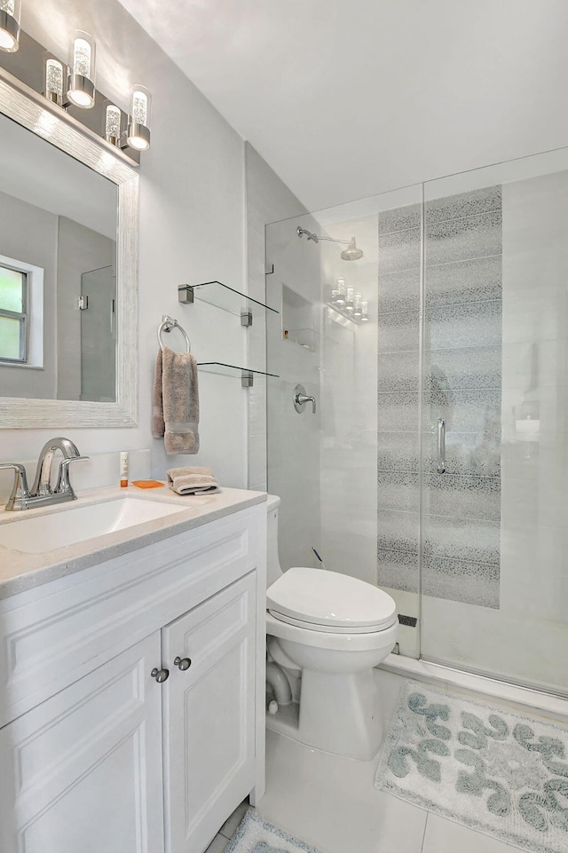 bathroom with tile patterned floors, vanity, toilet, and a shower with door