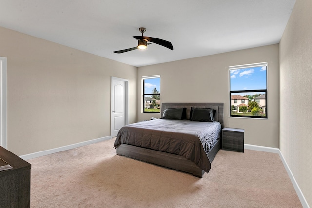 bedroom with multiple windows, ceiling fan, and light colored carpet