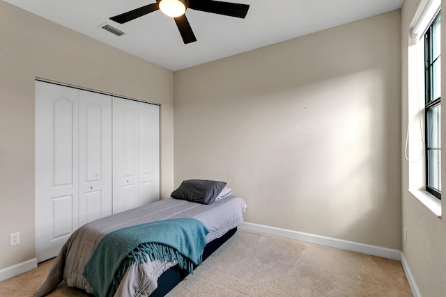 bedroom featuring ceiling fan, a closet, and light colored carpet