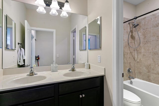 full bathroom featuring a notable chandelier, tiled shower / bath combo, toilet, and vanity