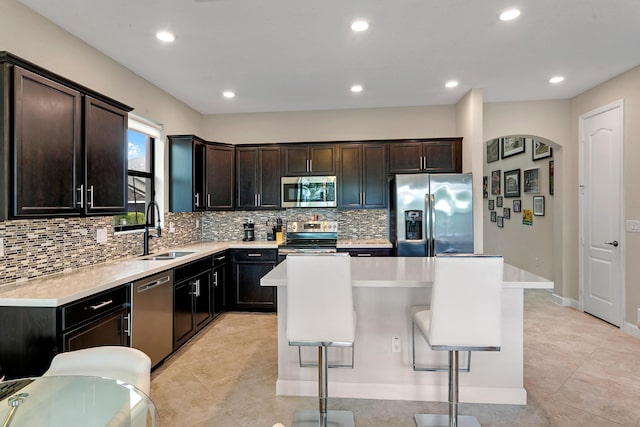 kitchen featuring sink, appliances with stainless steel finishes, tasteful backsplash, a kitchen island, and a kitchen bar